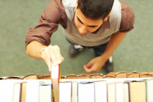 Student nimmt ein Buch aus einem Regal in der Bibliothek
