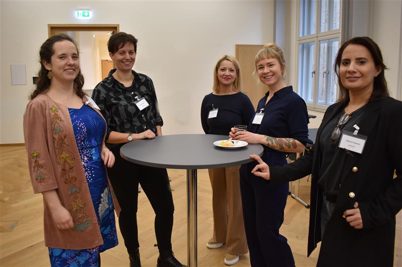 Fünf Frauen stehen an einem Stehtisch